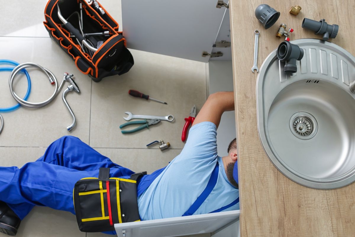Plumber with tools working under sink